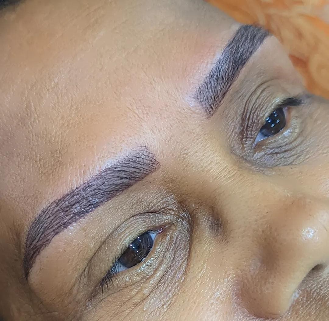 Close-up de rosto com sobrancelhas escuras e bem definidas, feitas com técnica de micropigmentação estética.